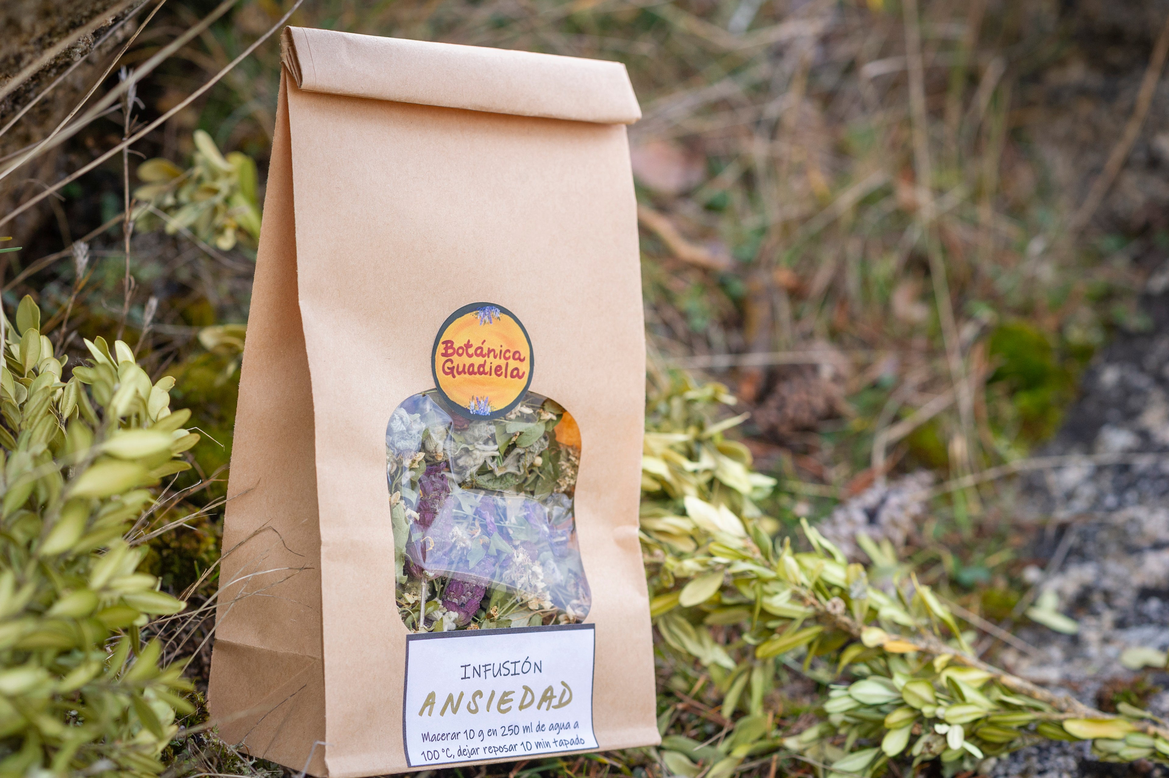 Bolsa de papel kraft con infusión Ansiedad de Botánica Guadiela, mezcla artesanal de plantas relajantes sobre fondo de bosque.