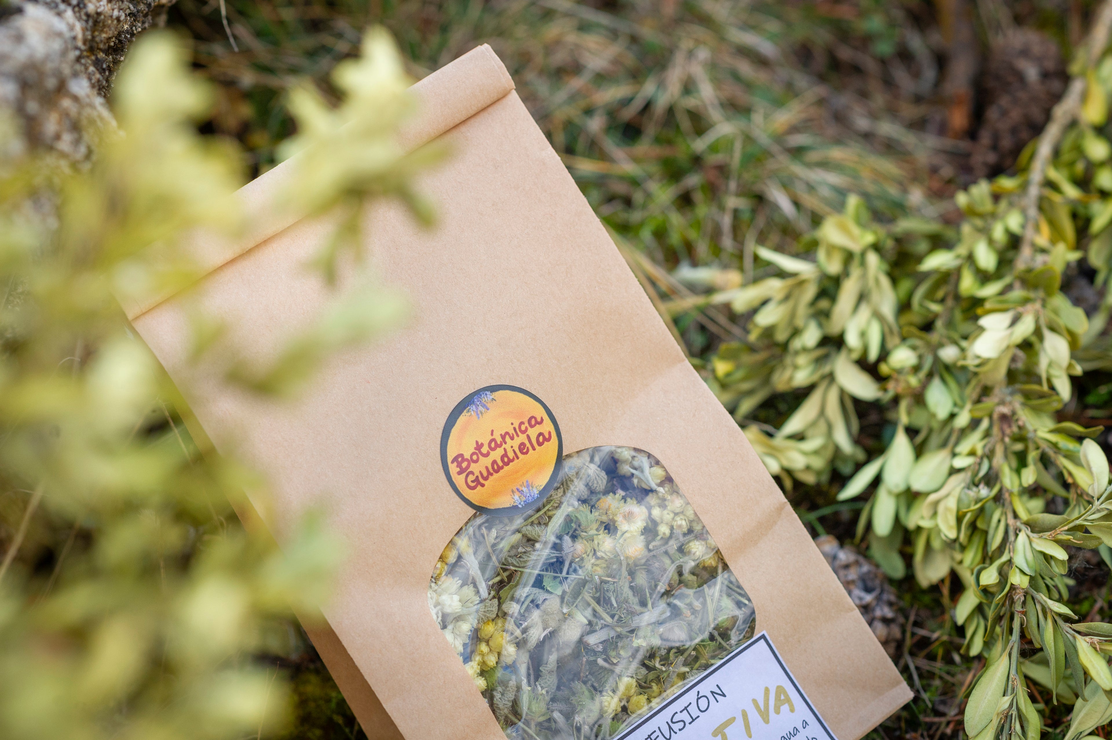 Bolsa de papel kraft de infusión Digestiva artesanal de Botánica Guadiela con manzanilla y plantas silvestres sobre fondo natural.