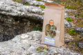 Bolsa de papel kraft con infusión Relajante artesanal de Botánica Guadiela, mezcla de flores y hojas silvestres sobre roca natural.