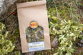 Bolsa de papel kraft con infusión Resfriado de Botánica Guadiela, mezcla artesanal de plantas silvestres secas en un entorno natural.