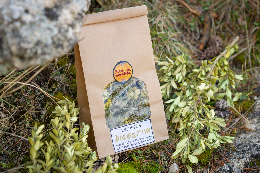 Bolsa de papel kraft de infusión Digestiva artesanal de Botánica Guadiela con manzanilla y plantas silvestres sobre fondo natural.