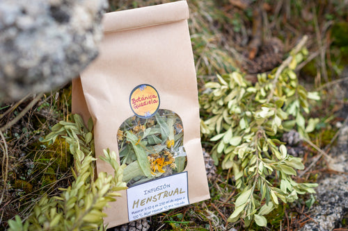 Bolsa de infusión Menstrual artesanal de Botánica Guadiela con mezcla de plantas silvestres sobre fondo de naturaleza.