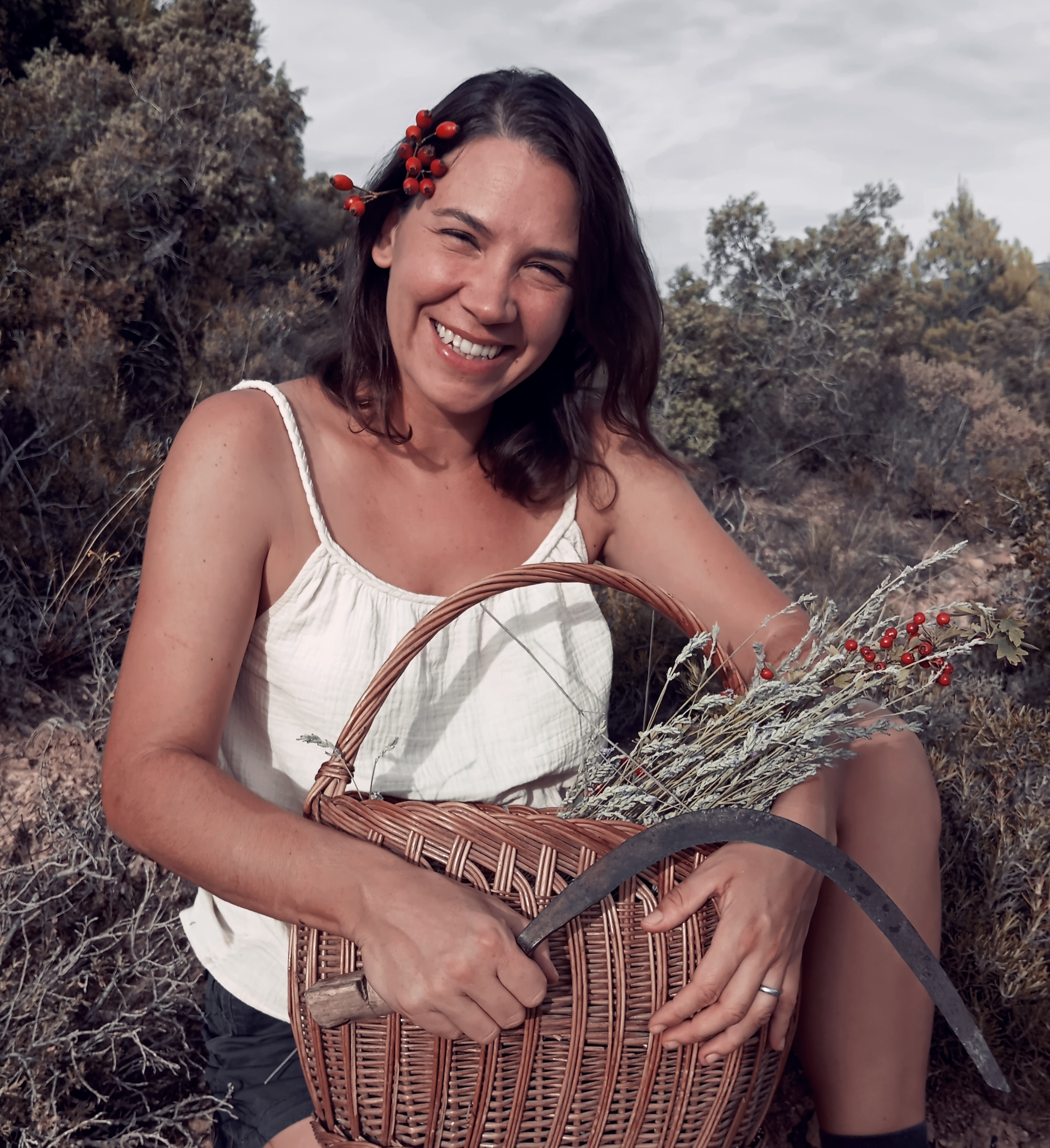 Sarka Voriskova recolectando plantas silvestres con cesta de mimbre y hoz para Botánica Guadiela en el campo.