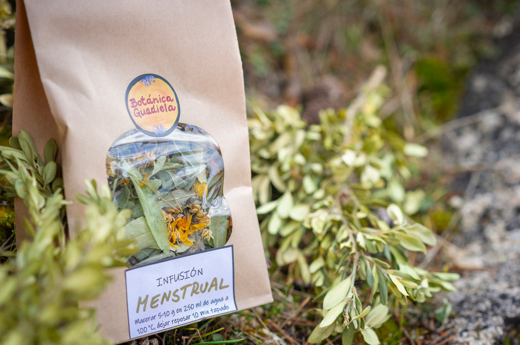 Bolsa de infusión Menstrual artesanal de Botánica Guadiela con mezcla de plantas silvestres sobre fondo de naturaleza.
